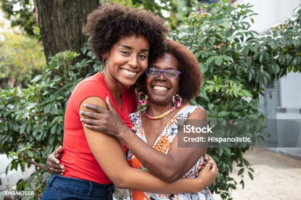 Portrait Of Beautiful Mother And Daughter Embracing Each Other While Looking At Camera With A Toothy Smile Stock Photo - Download Image Now