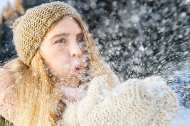 istock Young woman blowing snow from her gloved hands 1045465534