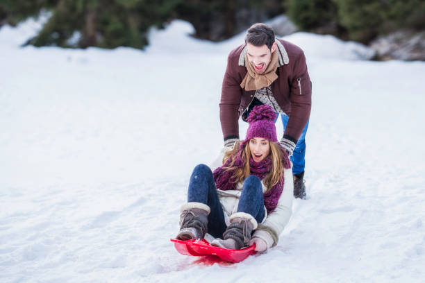 istock Man pushing his girlfriend riding a sled 1045465564