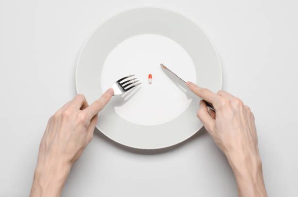 istock Medications and improper nutrition topic: human hand hold a plate with pills isolated on white background top view 1045465688