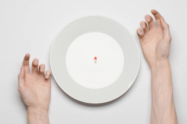 istock Medications and improper nutrition topic: human hand hold a plate with pills isolated on white background top view 1045465768