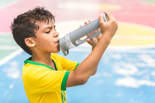 Boy drinking water on court