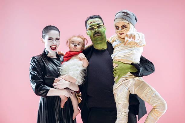 Halloween Family. Happy Father, Mother and Children Girls in Halloween Costume and Makeup Halloween Family. Happy Father, Mother and Children Girls in Halloween Costume and Makeup. Bloody theme: the crazy maniak faces on pink studio background face paint halloween adult men stock pictures, royalty-free photos & images