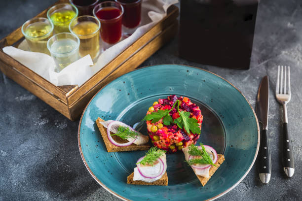 istock Russian beetroot salad vinaigrette, sandwich with fish and assorted alcoholic drinks. Black paper card of menu 1045478268