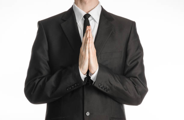 istock Businessman and gesture topic: a man in a black suit with a tie folded his hands in front of him and praying, meditating businessman isolated on a white background in studio 1045480634