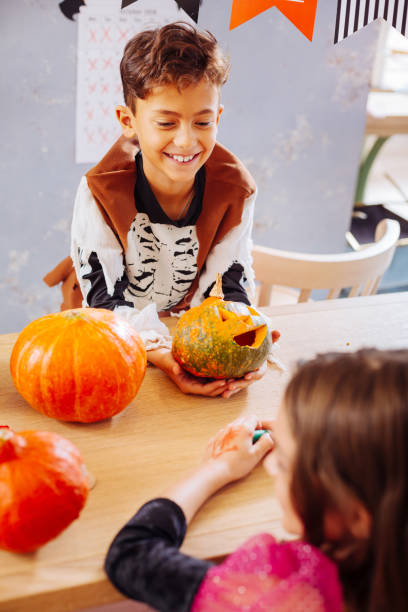 istock Curly dark-haired smiling boy wearing skeleton costume for Halloween 1045486402