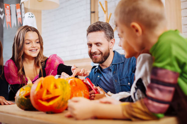 istock Handsome bearded father joining his children coloring and decorating pumpkins 1045486600