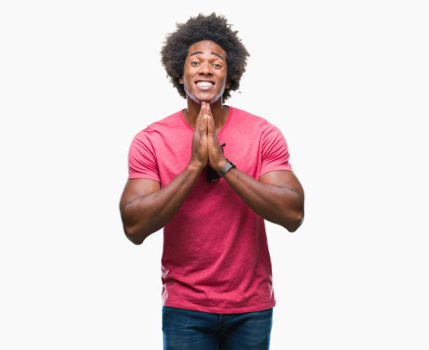 istock Afro american man over isolated background praying with hands together asking for forgiveness smiling confident. 1045487836
