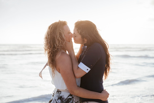 Young couple in love kissing on the deserted beach on a summer evening