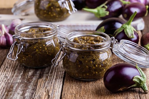 Eggplant preserves. Homemade vegetarian vegetable caviar in glass jar on rustic wooden table