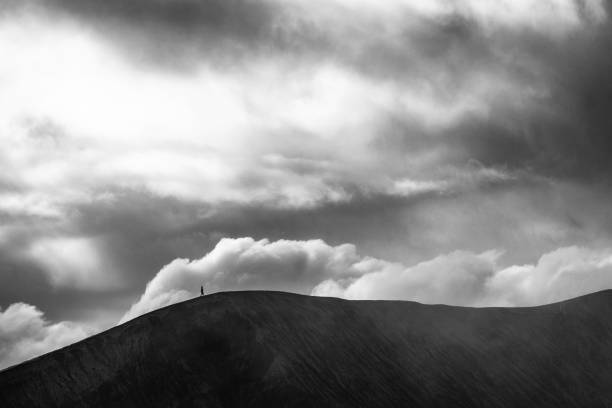 Active volcano mount Bromo in Indonesia Taking a walk on the crater rim of Mount Bromo in Indonesia under the heavy clouds and smoke coming out of the volcano sumeru stock pictures, royalty-free photos & images