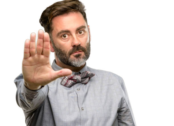 istock Middle age man, with beard and bow tie annoyed with bad attitude making stop sign with hand, saying no, expressing security, defense or restriction, maybe pushing 1045500348