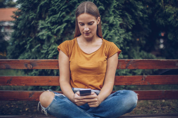 istock Young caucasian woman using phone in a city park 1045511400
