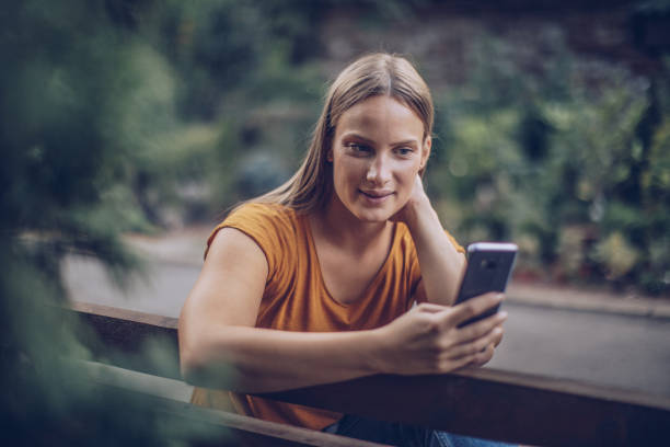 istock Young caucasian woman using phone in a city park 1045512472