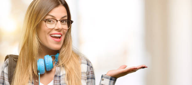 istock Young student woman with headphones and backpack holding something in empty hand 1045515162