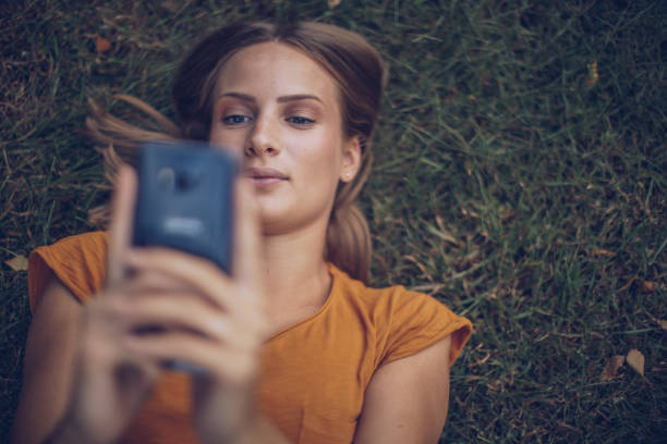 istock Young blonde woman lying on grass and using smartphone 1045515850