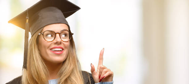 istock Young woman university graduate student happy and surprised cheering expressing wow gesture pointing up 1045522916