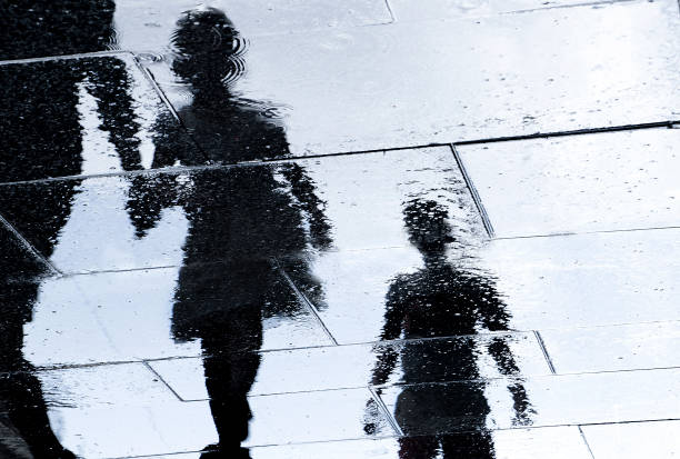 Blurry reflection silhouette of  people walking wet city street stock photo