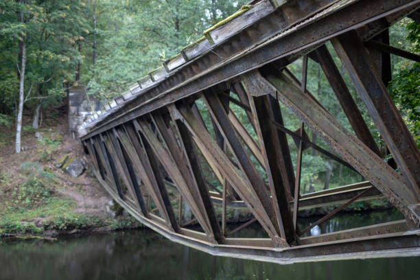 istock Old destroyed railway bridge over the river. Railway crossing blown up by sappers in central europe. Season of the autumn. 1045523718