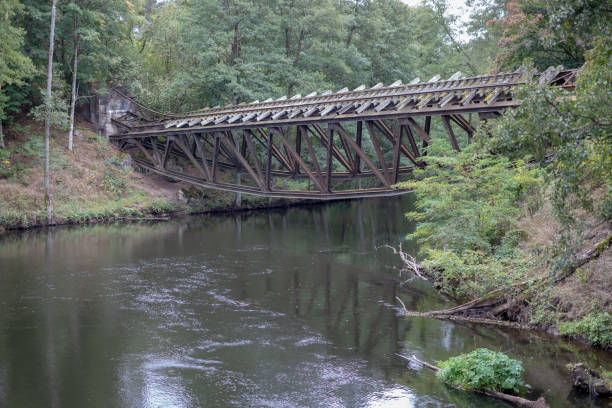 istock Old destroyed railway bridge over the river. Railway crossing blown up by sappers in central europe. Season of the autumn. 1045526378