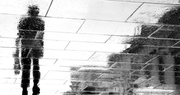 istock Blurry reflection  silhouettes of a man walking on a rainy day 1045528696