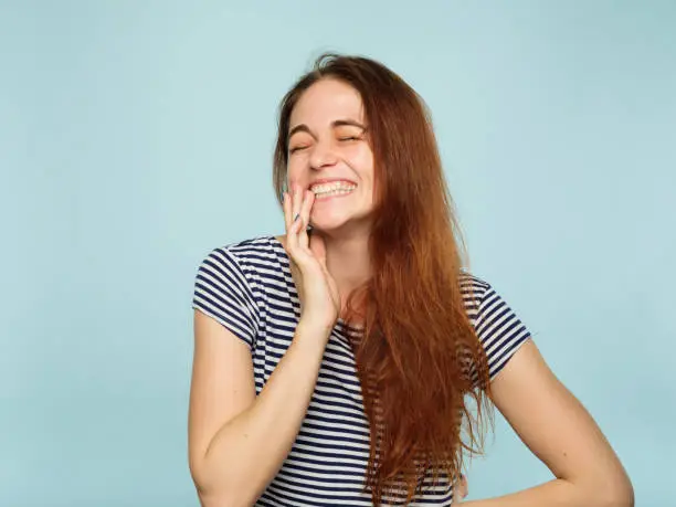 emotion face. very happy joyful thrilled to bits woman with beaming smile. young beautiful brown haired girl portrait on blue background.