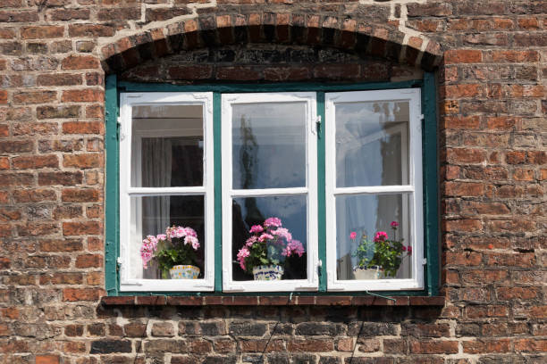 istock Windows in a red brick wall, with potted flowers 1045536642