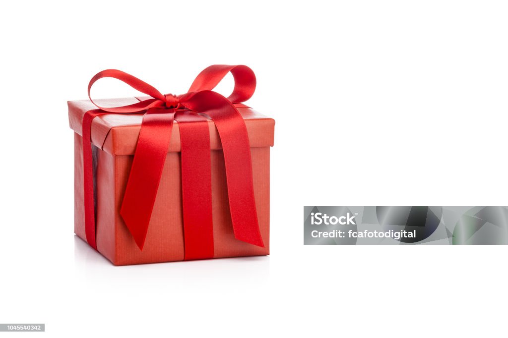 Red gift box with red ribbon isolated on white background Three-quarter front view of a square gift box wrapped with red craft paper shot on white background. The gift box is tied up with a red bow. Predominant colors are red and white. Useful copy space available for text and/or logo. DSRL studio photo taken with Canon EOS 5D Mk II and Canon EF 70-200mm f/2.8L IS II USM Telephoto Zoom Lens Gift Stock Photo