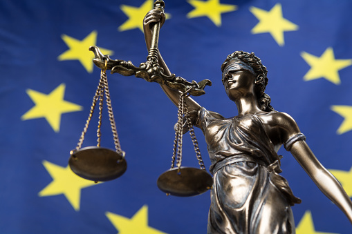 Estatua de la diosa con los ojos vendados de la justicia Themis o Justitia, contra una bandera europea, como un concepto jurídico photo