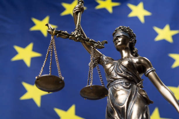 статуя с завязанными глазами богини правосудия фемиды или justitia, против европейского флага, как юридическое понятие - флаг европейского союза стоковые фото и изображения
