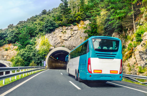 a white and blue coach, or long haul bus for tourists drives through the mountain tunnels and roads of northern spain, europe on a summer day. - bus coach bus travel tour bus imagens e fotografias de stock