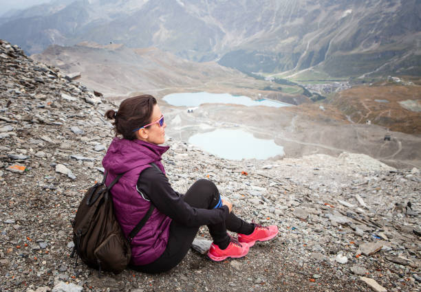 istock woman sitting with her backpack looking at the landscape 1045568592