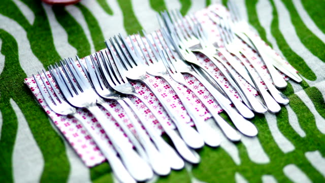 Many forks on napkin on the table.