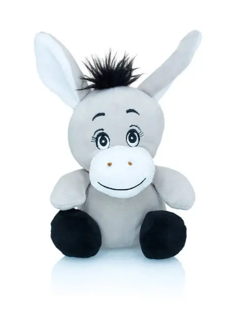 Grey smiling donkey plushie toy isolated on white background with shadow reflection. African wild ass plaything isolated on white underlay. Jackass plush stuffed puppet on white backdrop.