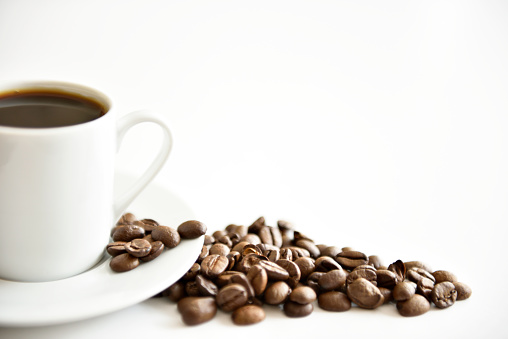 roasted coffee beans and a cup of coffee on white clear background