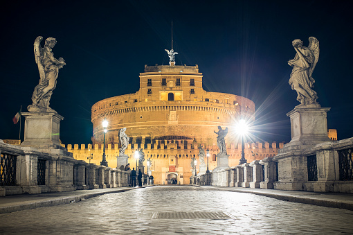 Sant' Angelo bridge and Castel Sant' Angelo (mausoleum of Hadrian) illuminated at night in the heart of Rome, Italy.