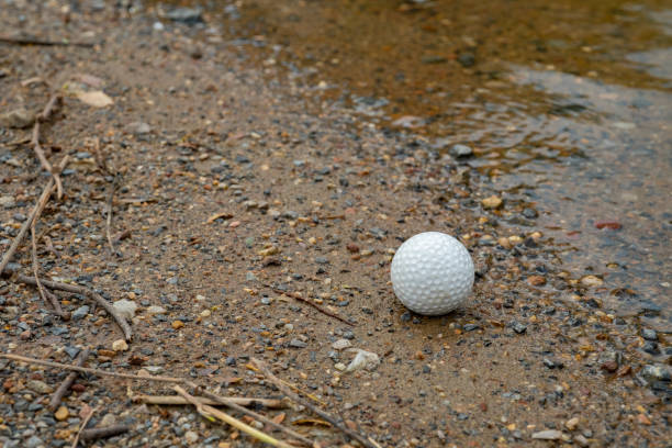 istock Golf ball on grass near small lake 1045652932