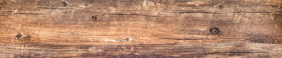 Wood texture background. Rustic rough wooden plank with nature color and pattern. Old knotted long board of wood close-up. Horizontal banner with vintage wood texture.
