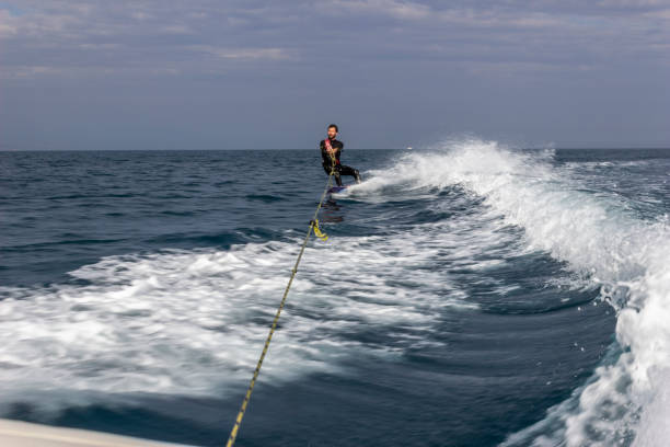 un adulto joven practicando wakeboarding en el agua de mar por un barco en la costa de málaga por el mediterráneo a un increíble deporte para practicar en un entorno salvaje en andalucía, españa - horizon over water environment vacations nature fotografías e imágenes de stock