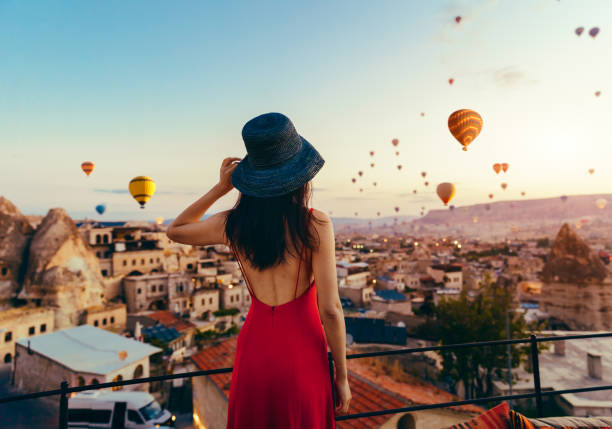 美しいアジアの女性は、カラフルな熱気球、トルコのカッパドキアでバレー上空を飛行を見ています。トルコ カッパドキア山の童話風景。 - トルコ ストックフォトと画像