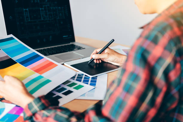 istock Freelance creative designers working on desk using digital graphic tablet and drawing with pen in modern home office. 1045747022