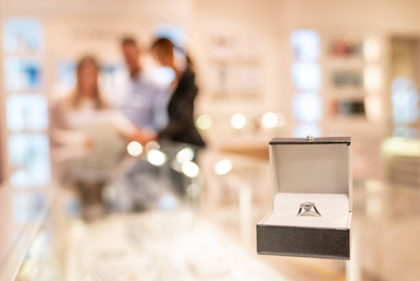 Couple buying an engagement ring at a jewelry store Couple buying an engagement ring at a jewelry store â focus on foreground jewelry store stock pictures, royalty-free photos & images