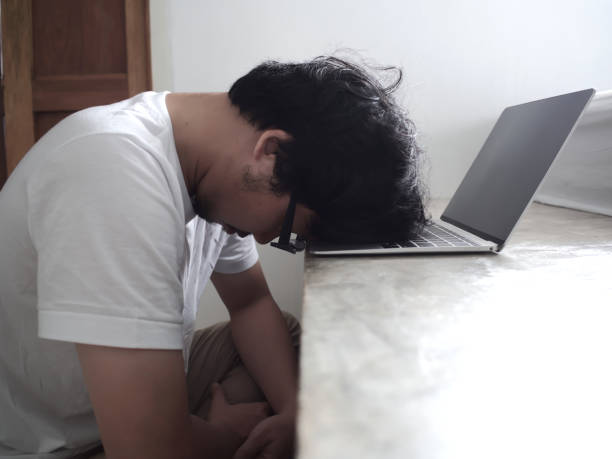 istock Tired upset young Asian man with head down on computer laptop. 1045767298