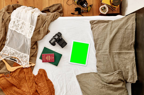 istock Digital tablet, passport and photo camera on messy bed - clipping path on screen 1045776056