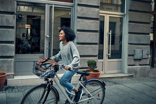 African Woman Riding Rented Bicycle In A City. Cycling and smiling.
