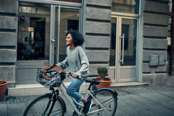 Woman Riding Rented Bicycle In A City African Woman Riding Rented Bicycle In A City. Cycling and smiling. travel destinations 20s adult adventure stock pictures, royalty-free photos & images