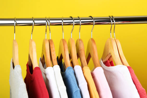 istock Wooden hangers with clothes on yellow background 1045829886