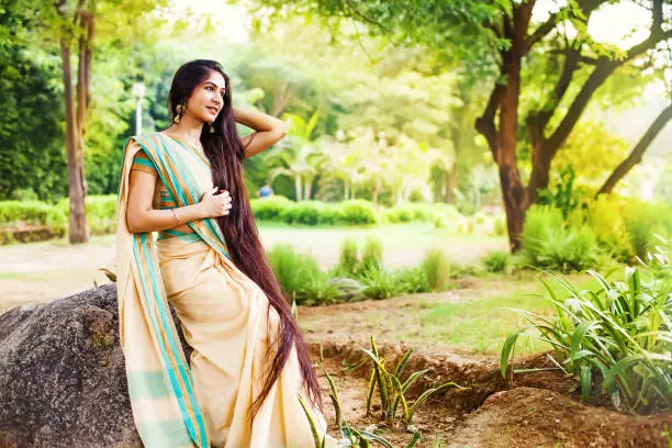 Beautiful indian woman with very long hair wearing saree in a park