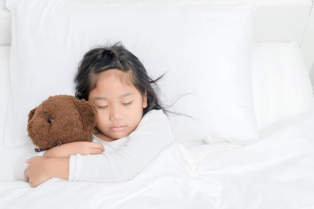 istock girl is hugging teddy bear while sleeping in bed 1045838070