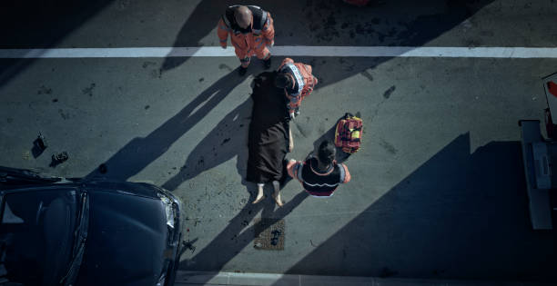 Paramedic team covering body of car crash victim with black sheet Paramedic team covering body of female victim of car accident with black sheet. unknown gender stock pictures, royalty-free photos & images